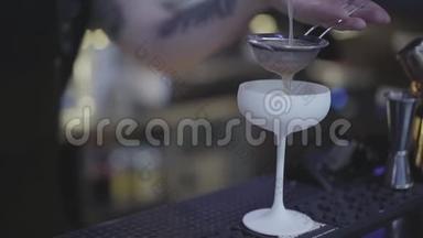 调酒师的手在令人惊叹的白色鸡尾酒杯中通过染色剂注入液体。 联合调酒师